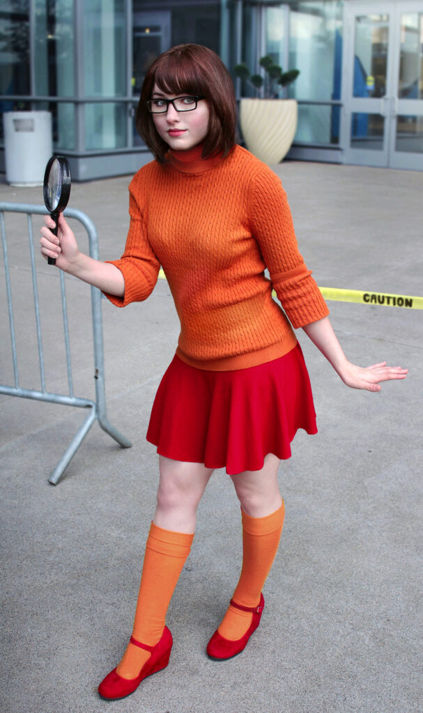 Chica haciendo cosplay de Velma sacandose los anteojos